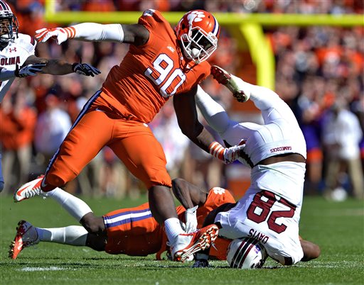South Carolina running back Mike Davis is upended by Clemson's Mackensie Alexander and Shaq Lawson (90) during the first half of an NCAA college football game in Clemson, S.C., Saturday, Nov. 29, 2014. (AP Photo/Richard Shiro)